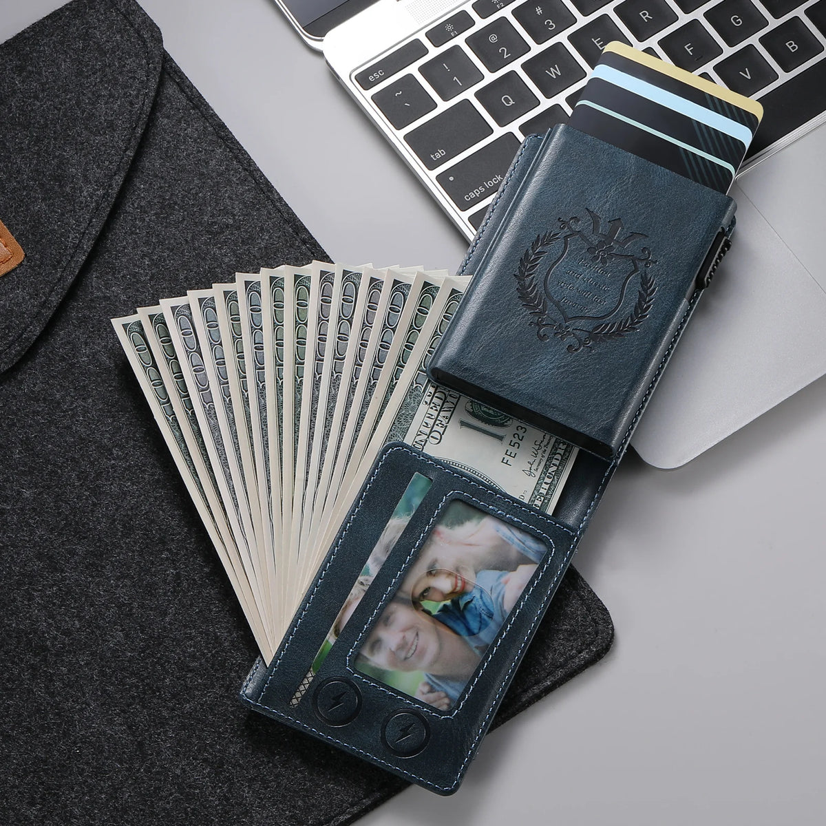 A dark blue anti-RFID blocking PU leather card holder with a leather sleeve and a stack of US dollar bills on a gray backgrou