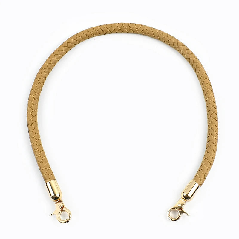 A close-up of a tan braided leather bag handle with a gold metal buckle.