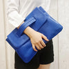 A hand holds a bright blue leather sequined crossbody clutch bag against a light background.