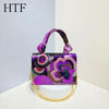 A purple and pink sequin embroidered floral clutch bag with a gold chain strap.