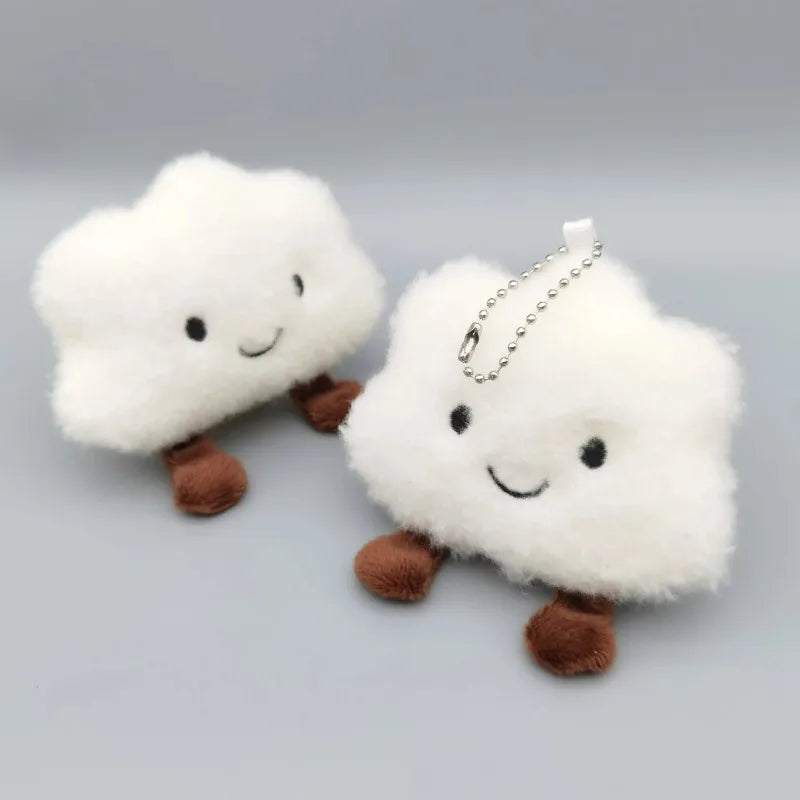 A white fluffy cloud shaped plush toy with a smiling face and a silver chain attached for a keychain.