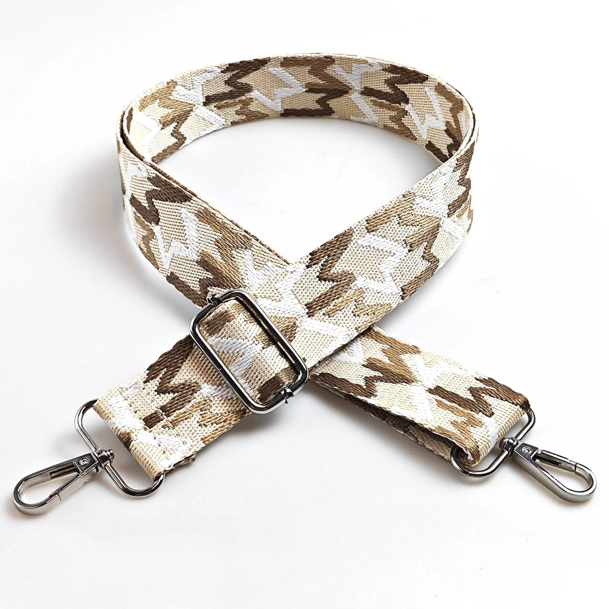 A beige and brown patterned jacquard strap for an adjustable wide crossbody bag.