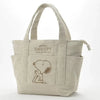A beige canvas shoulder bag featuring a Snoopy cartoon design.