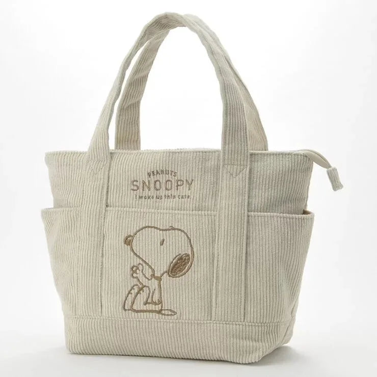 A beige canvas shoulder bag featuring a Snoopy cartoon design.