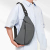 A person wearing a light blue shirt carries a black PU chest bag on their shoulder.