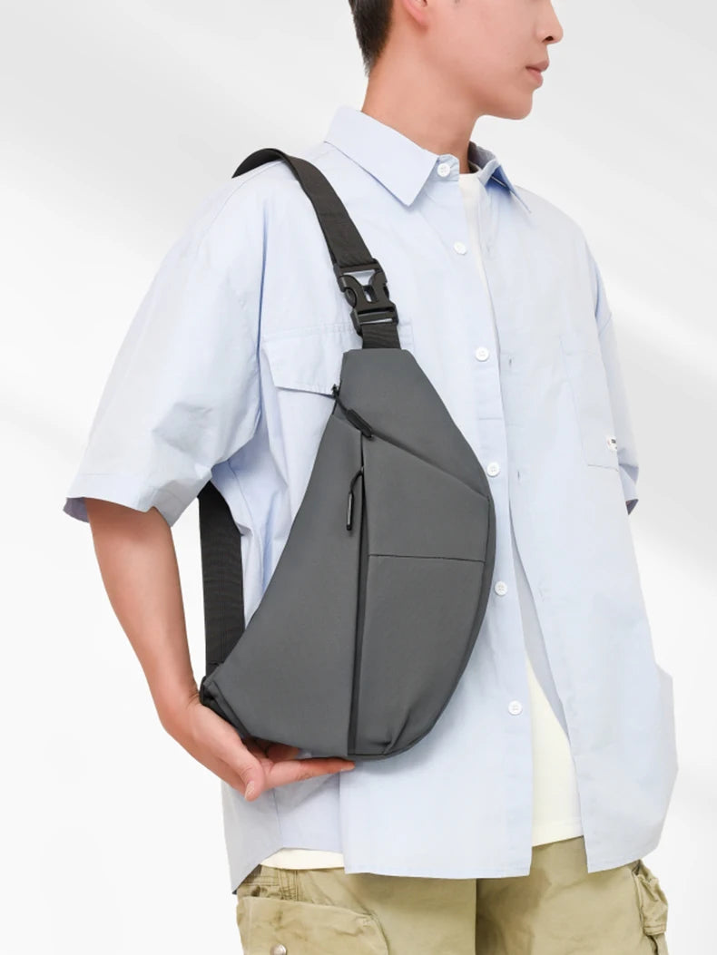 A person wearing a light blue shirt carries a black PU chest bag on their shoulder.