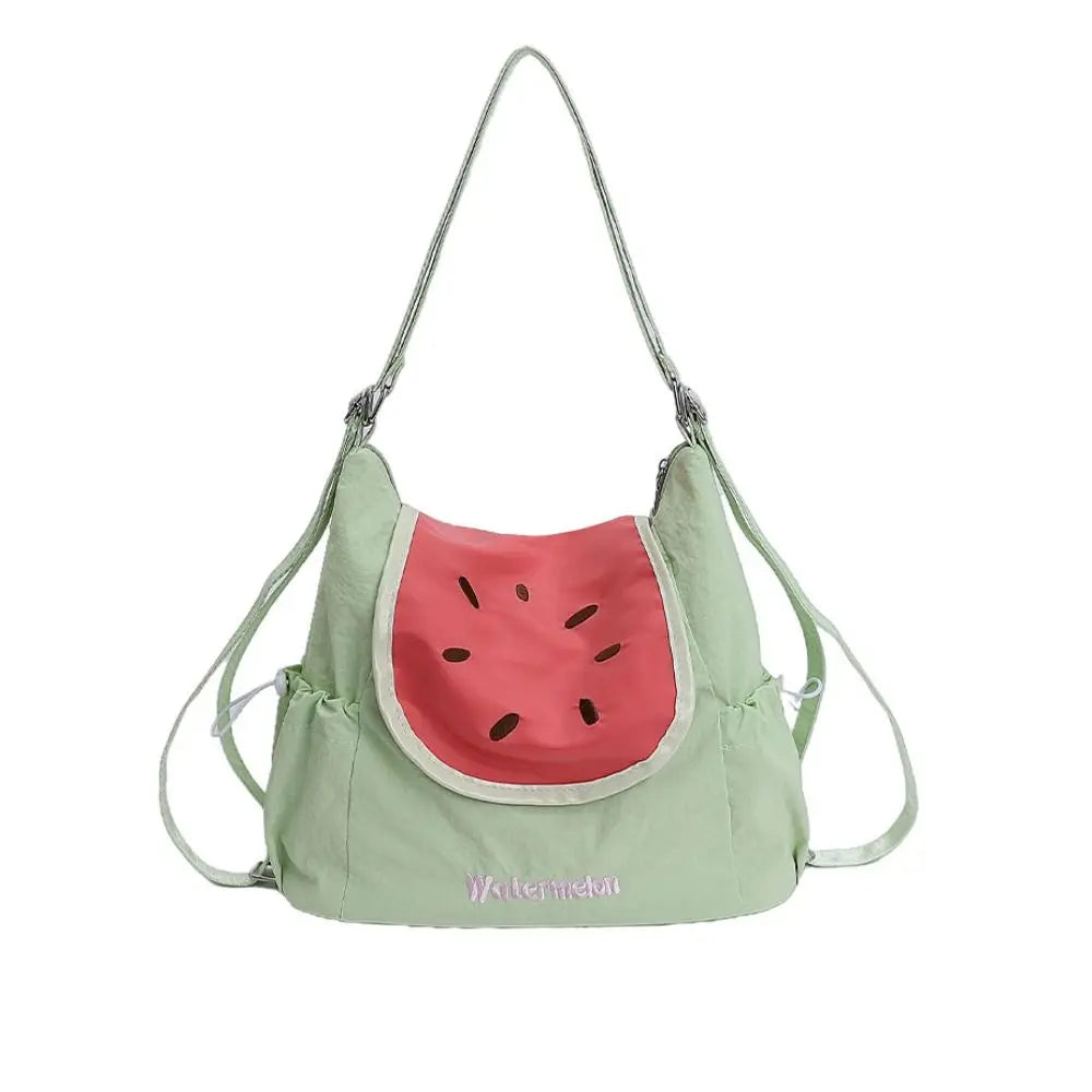 A light green nylon messenger backpack shaped like a watermelon slice with a pink rind and green seeds.