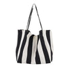 A black and white striped canvas tote bag with a long strap.