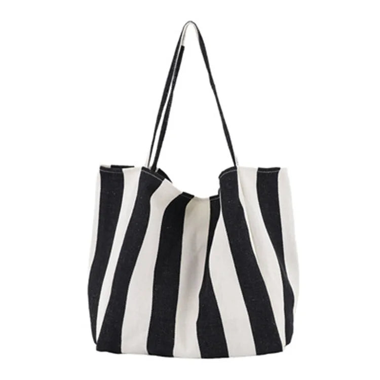 A black and white striped canvas tote bag with a long strap.