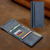A dark blue leather multi-card wallet with a slim design is shown next to a matching phone grip stand on a brown surface.