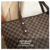A close-up of a black faux leather tote bag featuring a gold hardware detail and a monogram print.