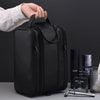 Une main tient un sac de toilette voyage en cuir PU noir haut de gamme pour hommes sur un fond sombre.