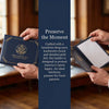 A dark navy leather birth certificate holder with gold foil detailing is held by hands, emphasizing its protective and elegan