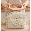 A light beige floral corduroy insulated lunch bag is shown being held over a wooden surface.