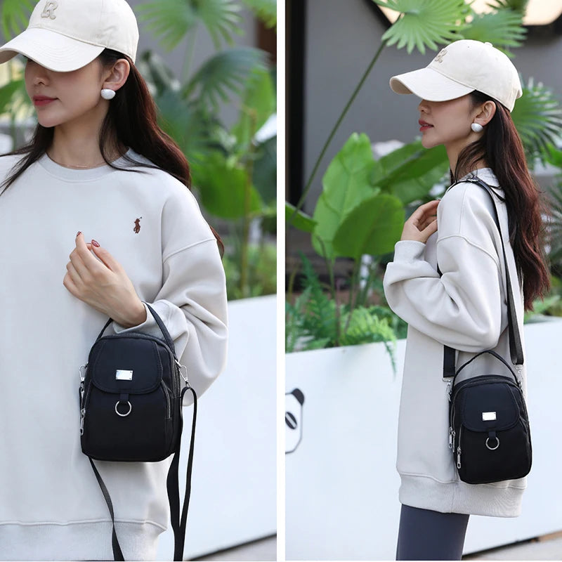 Une femme portant un sweat-shirt crème et un sac bandoulière floral noir.