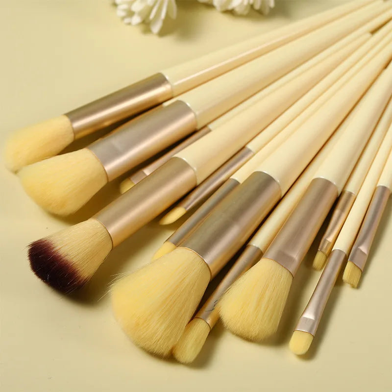 Un juego de trece brochas de maquillaje profesionales con mangos de madera clara y cerdas amarillas