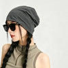 A woman wearing a gray slouchy knit beanie hat and sunglasses, looking to the side.