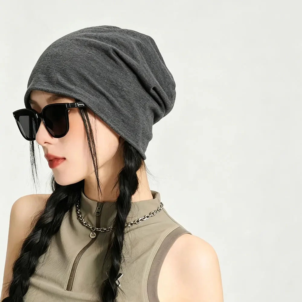 A woman wearing a gray slouchy knit beanie hat and sunglasses, looking to the side.