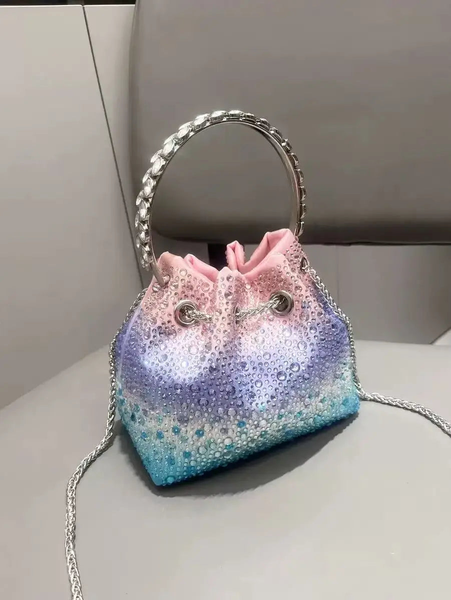 A purple and blue glittery fabric clutch with a pink drawstring and silver chain strap.