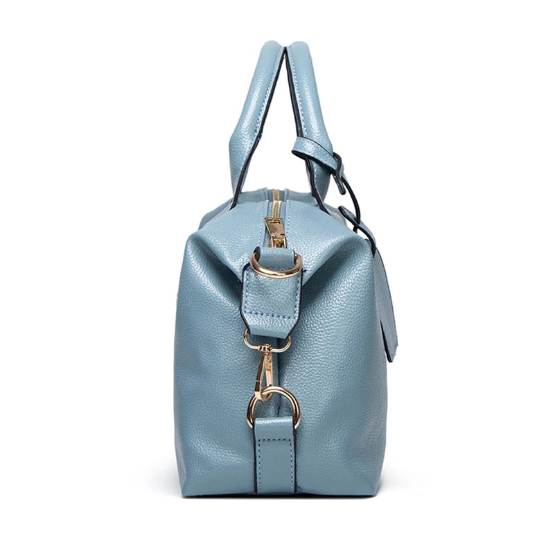 A light blue faux leather Boston handbag with silver hardware shown from the front.