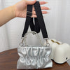 Silver pleated shoulder strap attached to a bag, held by a hand.