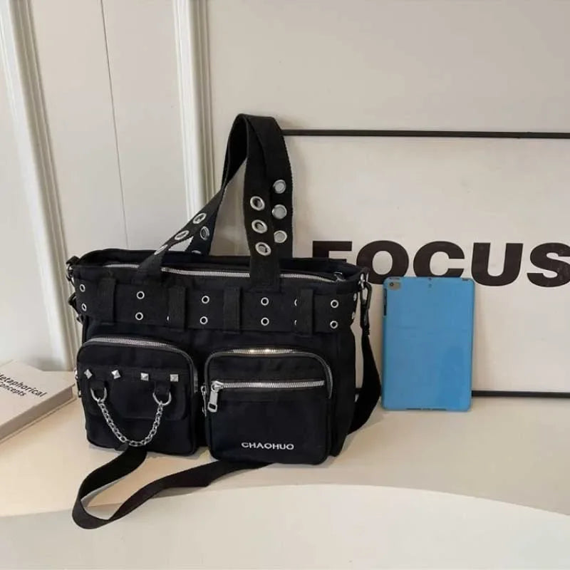 Black chains and rivet nylon shoulder bag with blue accents displayed on a white surface.
