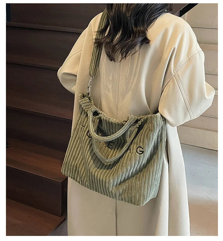 Sac à l'épaule en velours vert clair rayé porté par une personne en manteau crème.