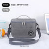 A gray insulated portable lunch bag with a strap is shown on a white marble surface.