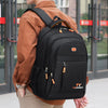 A person wearing a brown shirt is carrying a black TY Fashionbag double-shoulder travel backpack.
