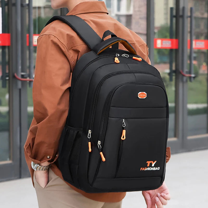 A person wearing a brown shirt is carrying a black TY Fashionbag double-shoulder travel backpack.