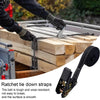 Close-up of heavy duty ratchet tie-down straps being used to secure wooden planks on a flatbed.