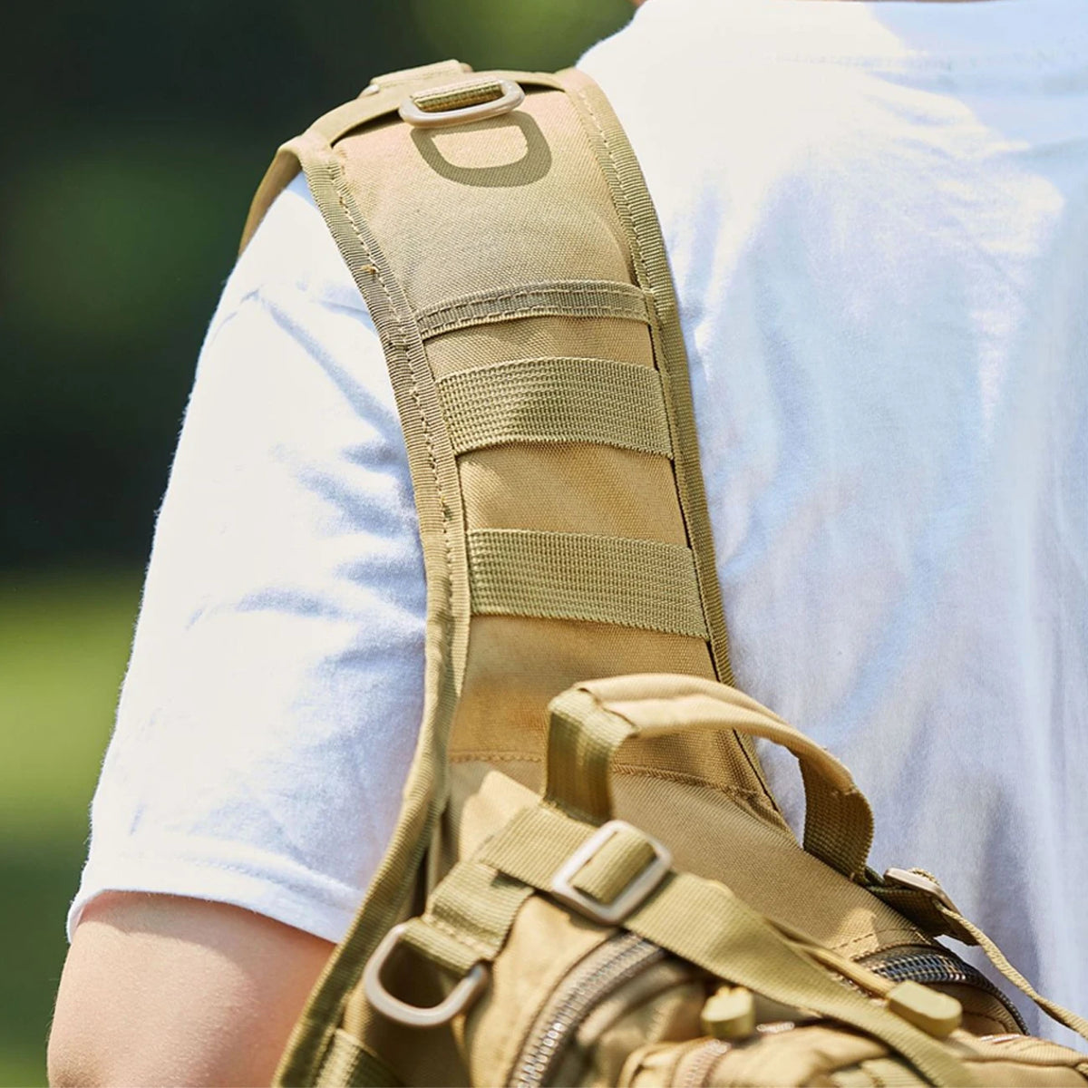 A close-up view of a tan multi-compartment crossbody and chest bag worn on a person's shoulder.