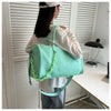 A person is holding a mint green crocodile grain PU leather travel duffle bag with a light green strap.