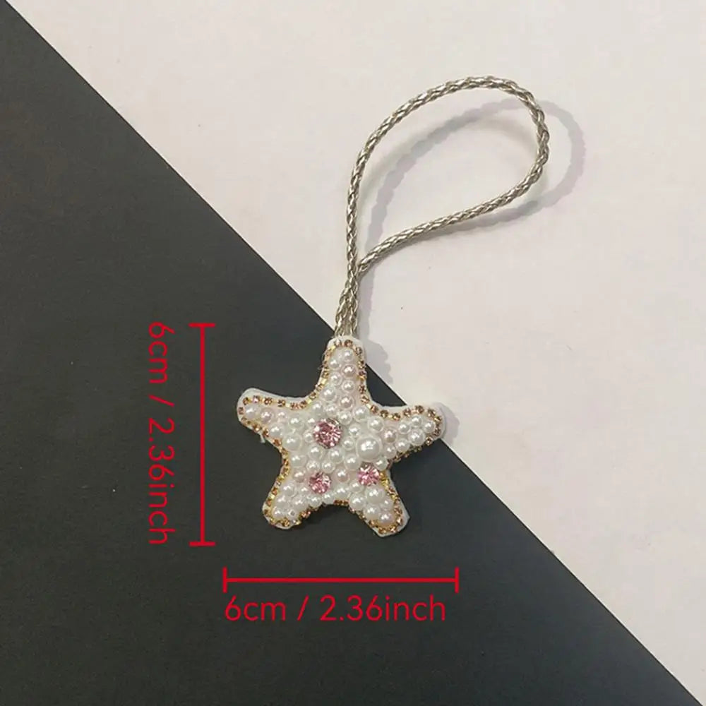 A silver beaded bag charm shaped like a star with pink and white rhinestones.