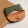 A brown leather card holder with a green leather flap and a tan suede insert.