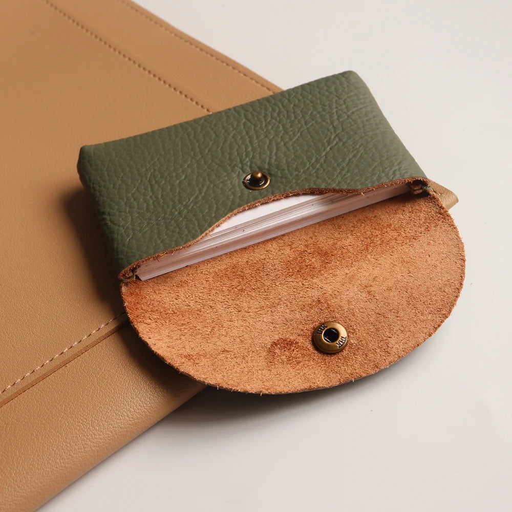 A brown leather card holder with a green leather flap and a tan suede insert.