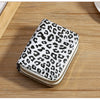 A small wallet with a leopard print fabric and a gold-toned zipper is placed on a wooden surface.