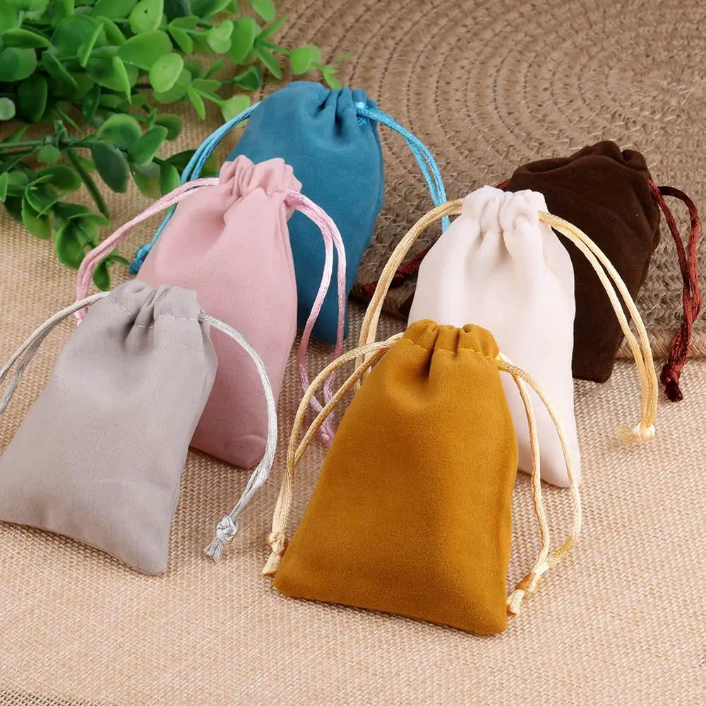 Un juego a granel de bolsas de regalo de terciopelo suave con cordón en varios colores, incluyendo rosa, azul, beige y marrón