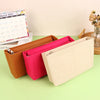 A set of felt cosmetic bag insert organizers in shades of orange, pink, and beige are displayed next to a calendar.