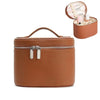 A round, tan leather travel makeup organizer with a zipper closure and an open compartment for brushes.