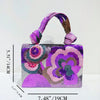 A purple sequin embroidered floral clutch bag with a purple strap and intricate floral designs.