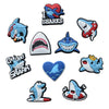 A collection of decorative shoe charms and pins featuring shark designs in various colors and styles.