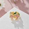 Gold-toned aesthetic flower butterfly rings with pink and green enamel set against a white background.