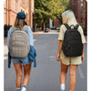 Two female students walk on a street with backpacks during college commutes.