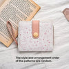 A pink and white patterned cat cartoon coin purse and card holder wallet resting on a white surface next to an open book.
