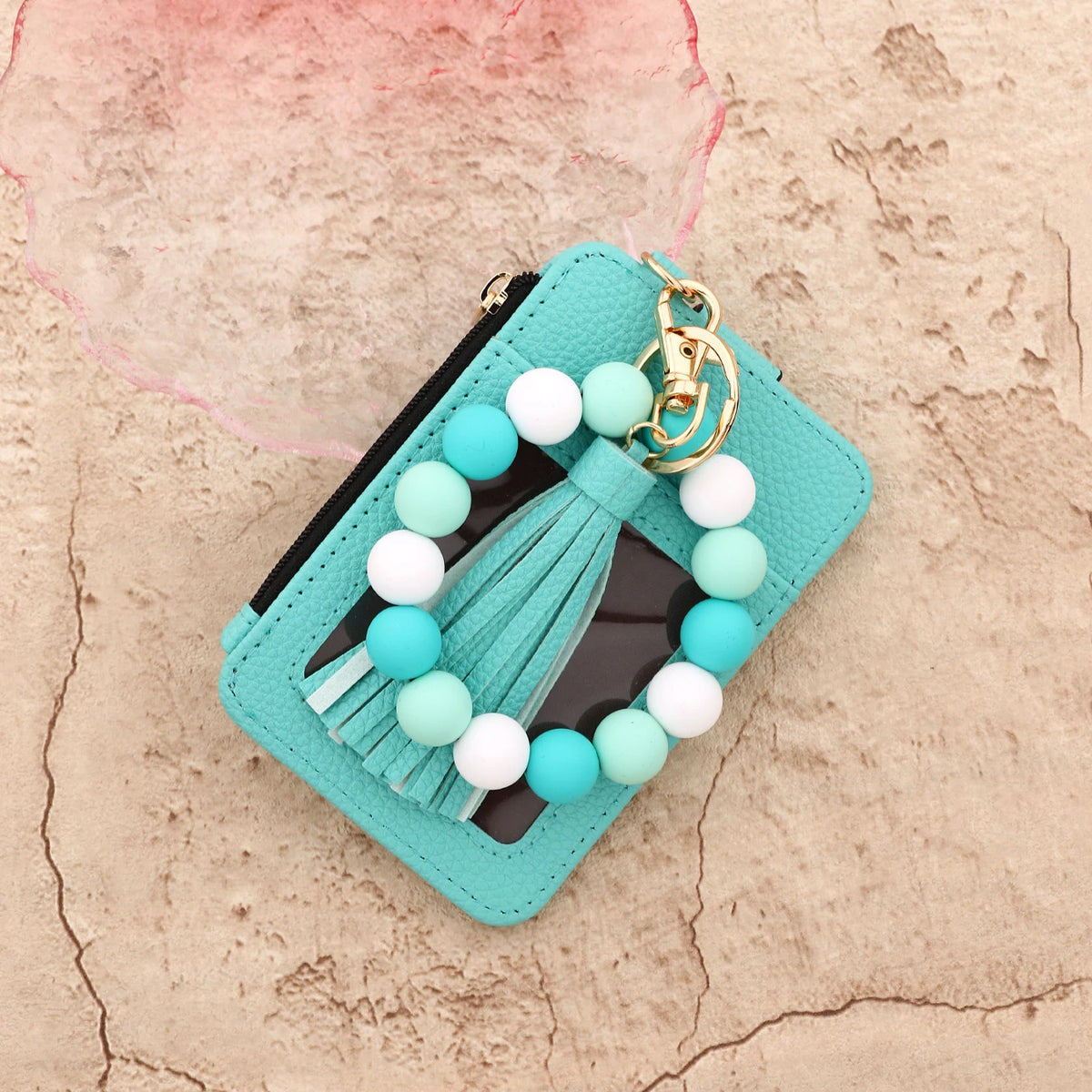 A turquoise leather card holder with a white and light blue beaded tassel keychain.