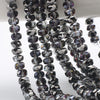 A close-up of dark purple and gray AB faceted crystal glass beads strung together for jewelry making.