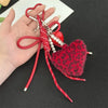 A red and black leopard print plush heart pendant keychain with red string and pearl beads.