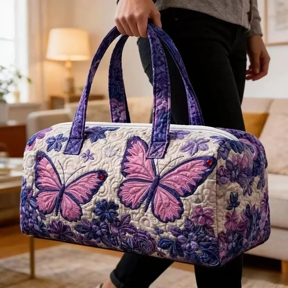 A quilted purple and white travel duffel bag with a butterfly pattern being held by a person.