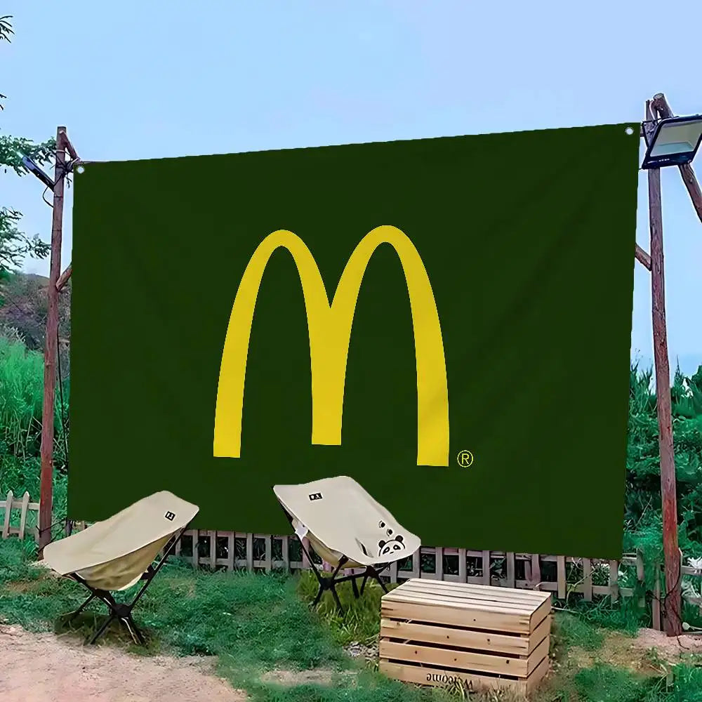 A large green banner featuring the yellow McDonald's 'M' logo, displayed outdoors with wooden pallets and a small table.